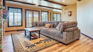 A spacious living room with a large sectional sofa, a wooden coffee table, and a patterned rug. - Million-Dollar Views! 'Gilded Loon' w/ Fire Pit (Gilford)
