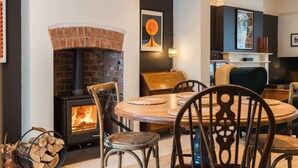 A cozy living room with a brick fireplace, a round wooden dining table, and chairs.