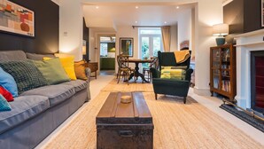 A living room with a grey sofa, a green armchair, a wooden coffee table, and a bookshelf.