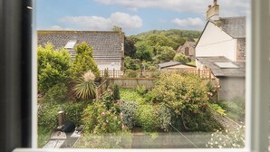 A residential area with houses, a garden with various plants and flowers, and a clear sky.