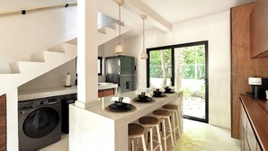 Una cocina moderna con lavadora integrada, una barra con taburetes y un amplio ventanal con vistas al exterior.