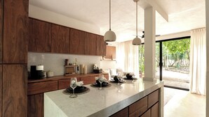 Una cocina moderna con armarios de madera, encimera de mármol y luces colgantes.