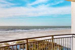 A balcony with a view of the beach and ocean.