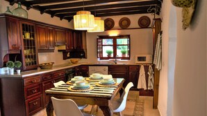 Una cocina con armarios de madera, una mesa de comedor para cuatro personas y una ventana con plantas en macetas.