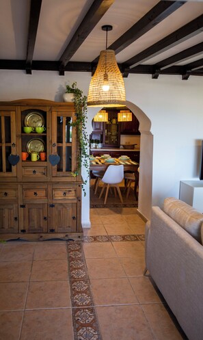 Un salon chaleureux avec un meuble en bois, un coin repas avec une table et des chaises, et un luminaire suspendu.