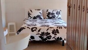 Un dormitorio con cama, una silla y un armario.
