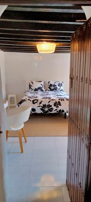 A bedroom with a bed, a chair, and a wardrobe.