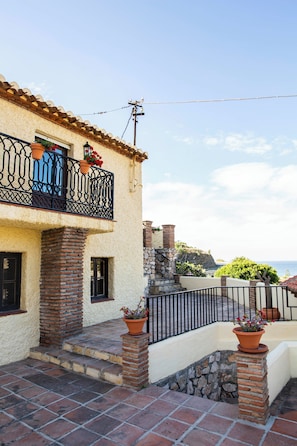 A building with a balcony, stone pillars, and a view of the sea.