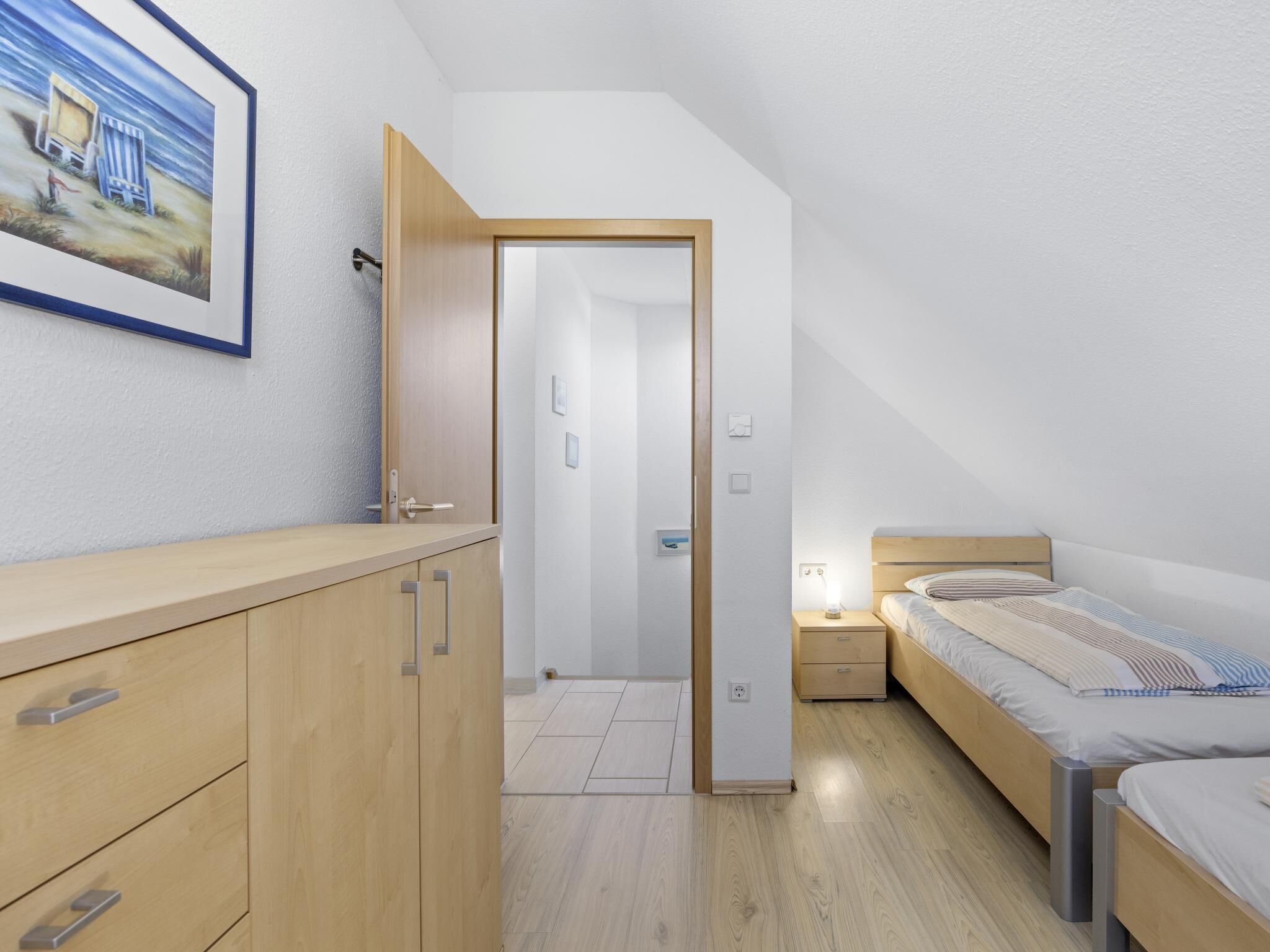 Un dormitorio moderno con un aparador de madera, una cama con cabecera y un cuadro en la pared.