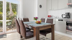 A modern kitchen with white cabinets, a stainless steel range hood, and a built-in oven. - Holiday home with sauna on the Baltic Sea (Boiensdorf)