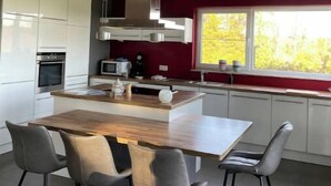 A modern kitchen with a central island, white cabinets, stainless steel appliances, and a red accent wall.