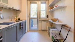 Una cucina con una finestra, un termosifone e scaffali con cesti.