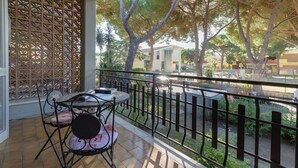 Un balcone con ringhiera in metallo, un tavolo con sedie e un pannello decorativo.