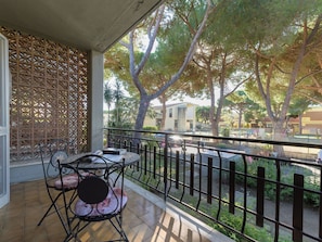 A balcony with a metal railing, a table with chairs, and a decorative screen.