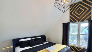 Une chambre à coucher moderne avec un lit, une table de chevet, une lampe et une fenêtre avec des rideaux.