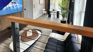 Une chambre d’hôtel moderne dotée d’un balcon, d’un coin repas et d’un espace de vie comprenant un canapé et une table basse.
