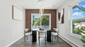 Un coin repas avec une table ronde, quatre chaises et un lustre moderne.