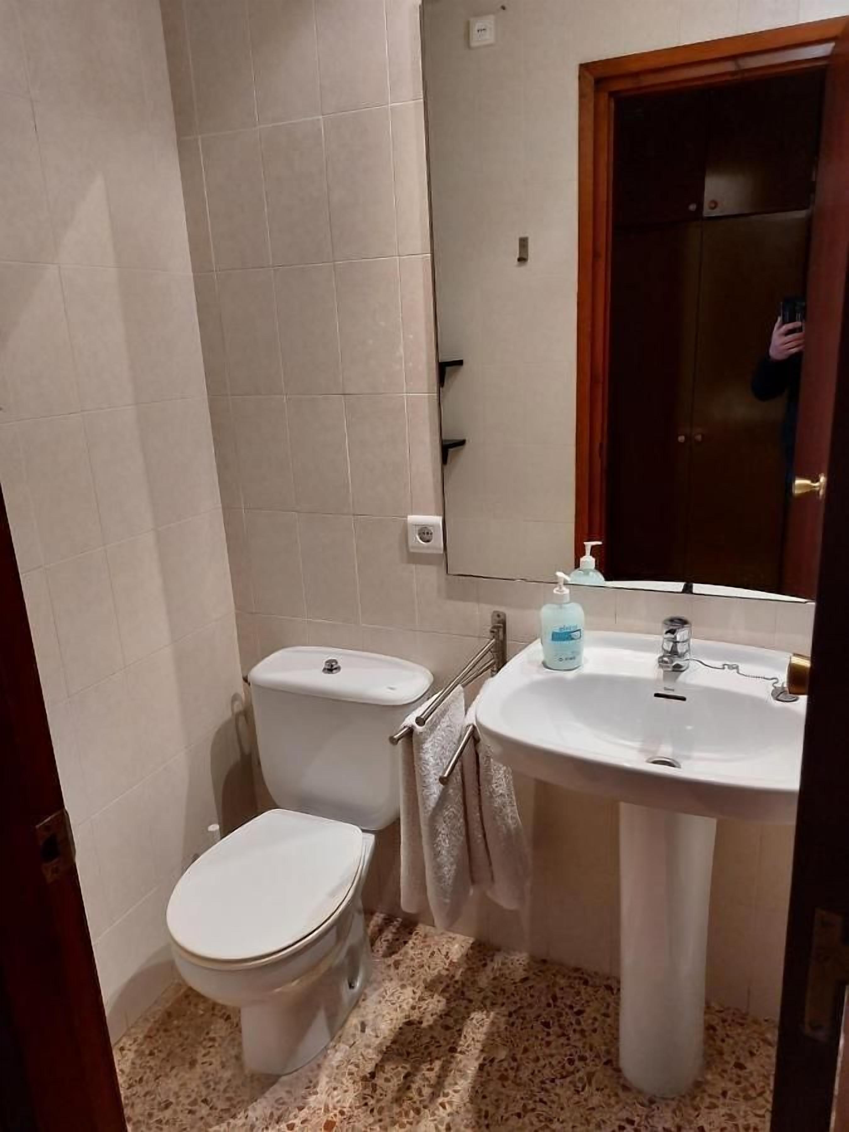 A small bathroom with a toilet, sink, and mirror.