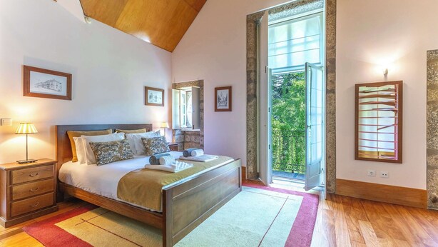Ein Schlafzimmer mit Bett, Nachttischen, einem Fenster und Blick ins Grüne.