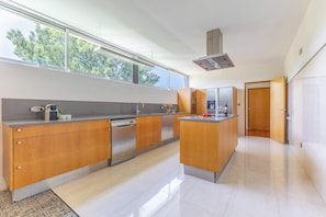 Una cocina moderna con armarios de madera, electrodomésticos de acero inoxidable y un amplio ventanal que proporciona luz natural.