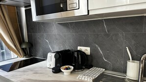 Una cocina moderna con microondas, tostadora, cafetera y un bol de fruta en la encimera.