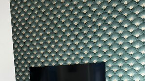 Una sala de estar moderna con un televisor de pantalla plana montado en una pared con un papel tapiz de diseño con motivos de abanicos.