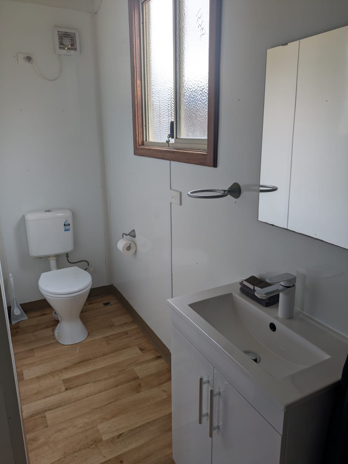 Ein kleines, kompaktes Badezimmer mit Toilette, Waschbecken und Schrank.