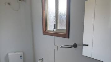 Ein kleines, kompaktes Badezimmer mit Toilette, Waschbecken und Schrank.