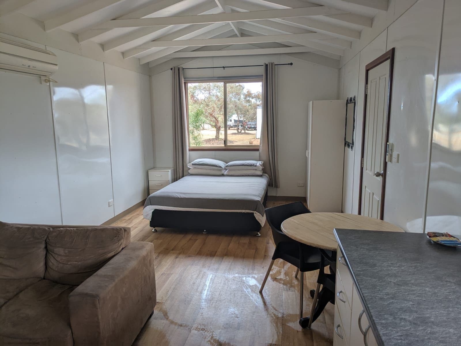 A room with a bed, a small table, a couch, and a window with curtains.