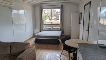 A room with a bed, a small table, a couch, and a window with curtains.