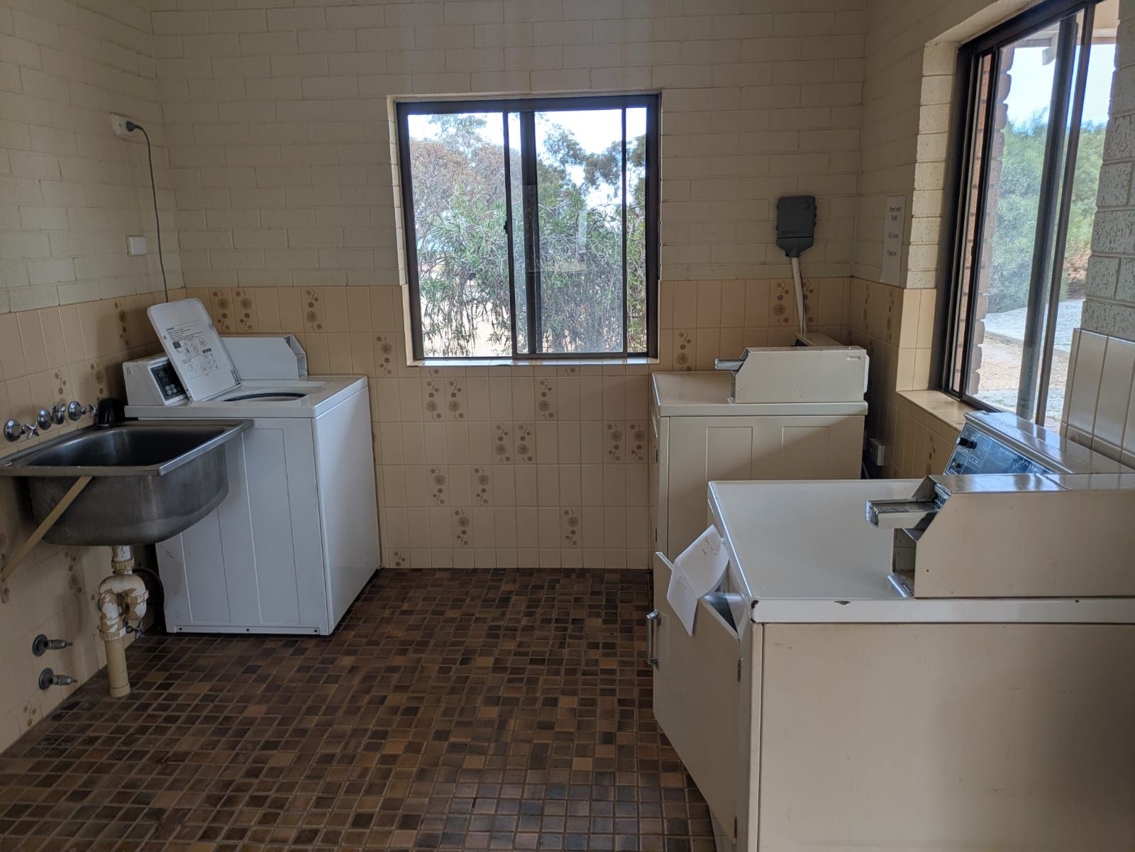 A compact kitchen with a washing machine, a sink, and a window providing natural light.