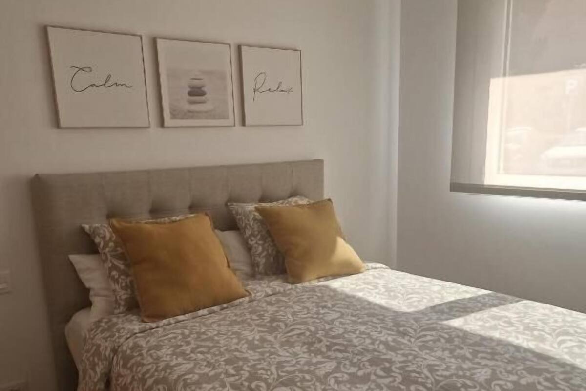 Une chambre à coucher avec un lit, deux oreillers, une tête de lit et une fenêtre.