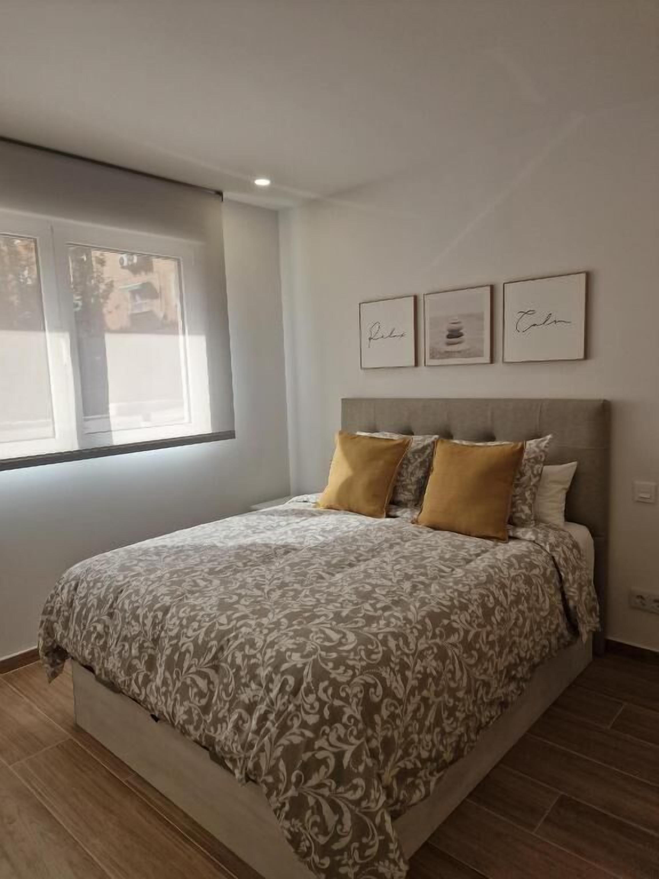 Ein Schlafzimmer mit einem Bett, einem Fenster und drei gerahmten Bildern an der Wand.