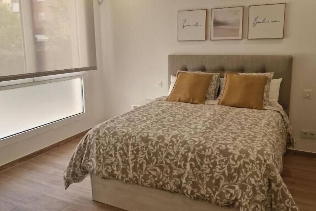 Une chambre à coucher avec un lit, une fenêtre et trois tableaux encadrés accrochés au mur.