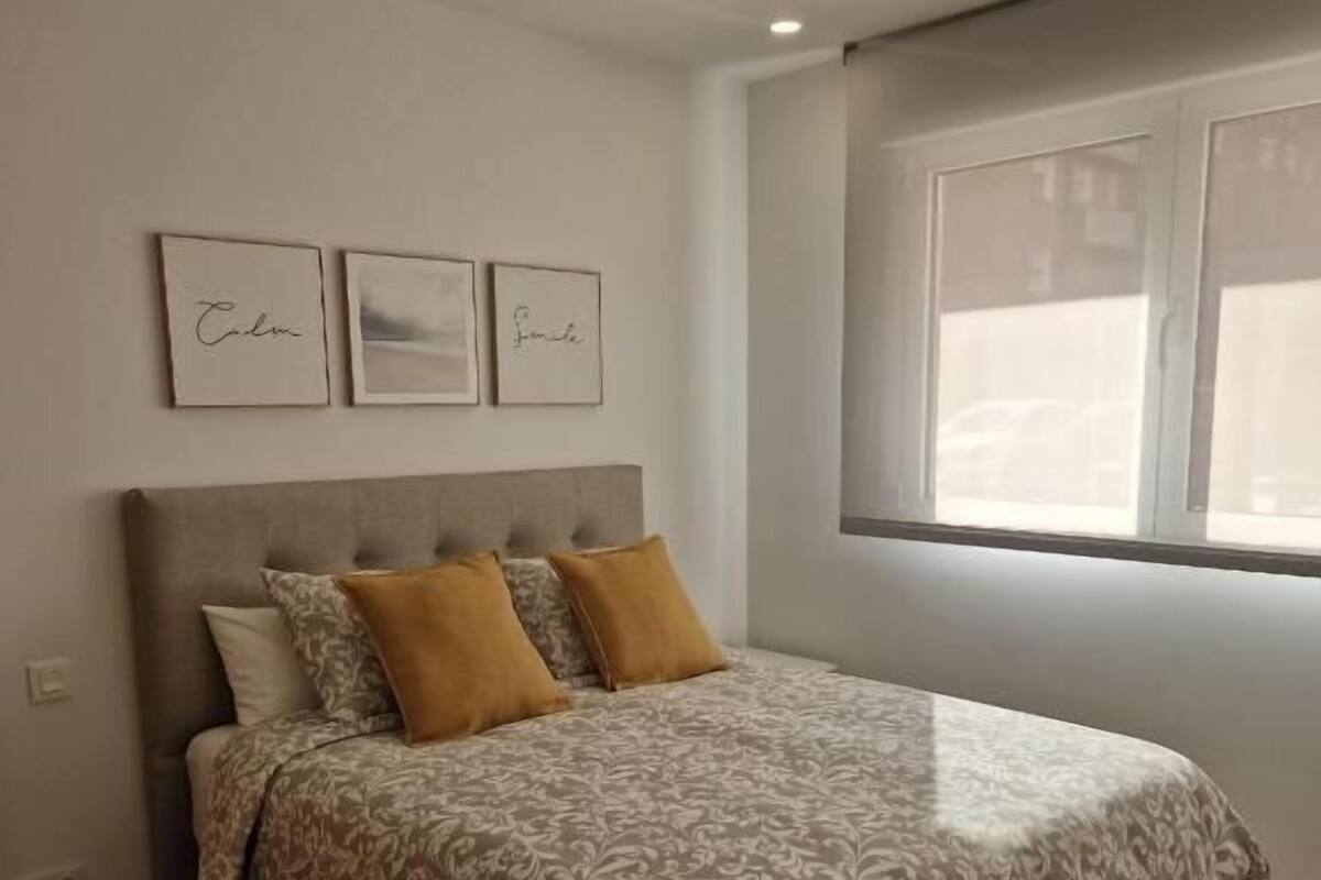 Une chambre à coucher avec un lit, deux oreillers, une tête de lit et trois tableaux encadrés accrochés au mur.