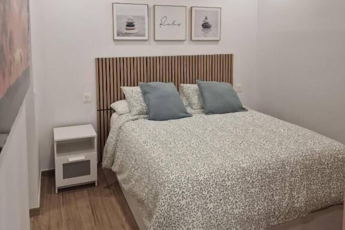 Une chambre à coucher avec un lit, une table de chevet et trois tableaux encadrés accrochés au mur.