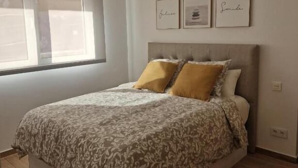Una camera da letto con un letto, una finestra e tre quadri appesi al muro.