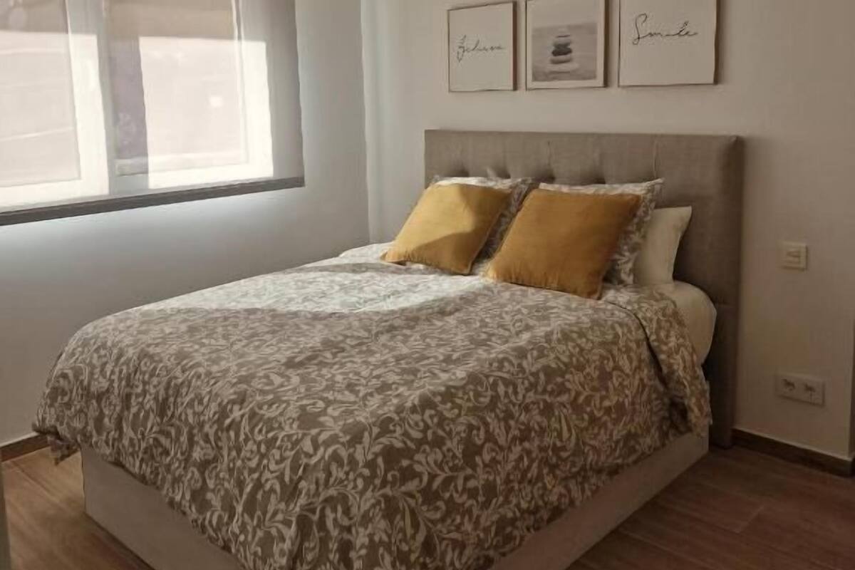 Une chambre à coucher avec un lit, une fenêtre et trois tableaux encadrés accrochés au mur.