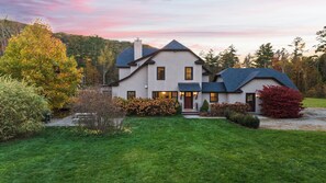 A two-story house with a well-maintained lawn and a driveway leading to the entrance. - Spacious Living, Covered Porch & Forest Setting | Beaver Creek by AvantStay (Stockbridge)