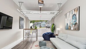 Ein modernes Wohnzimmer mit einem weißen Sofa, einem blauen Sitzsack und einem farbenfrohen Teppich.