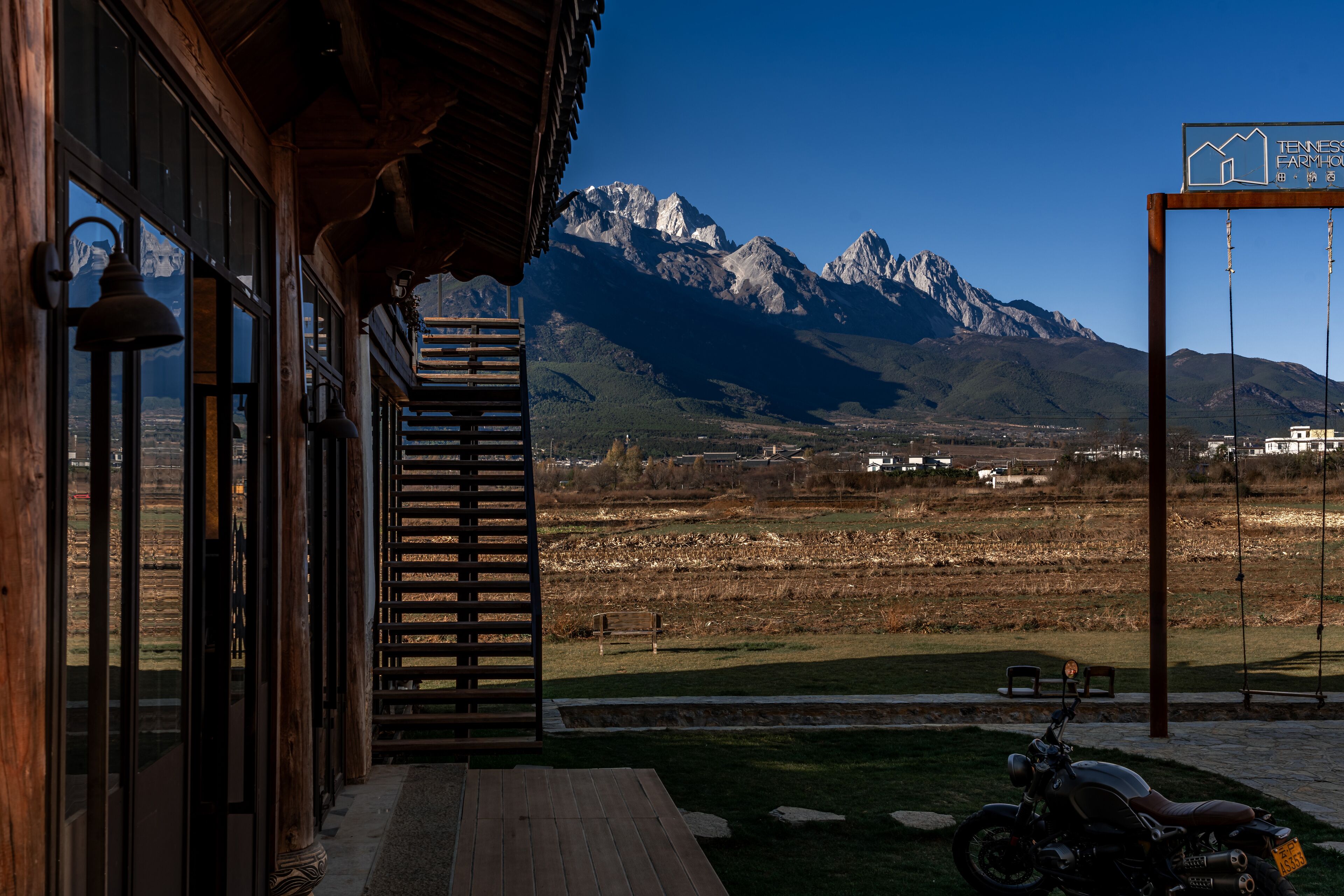 A wooden building with large windows overlooking a mountainous landscape.