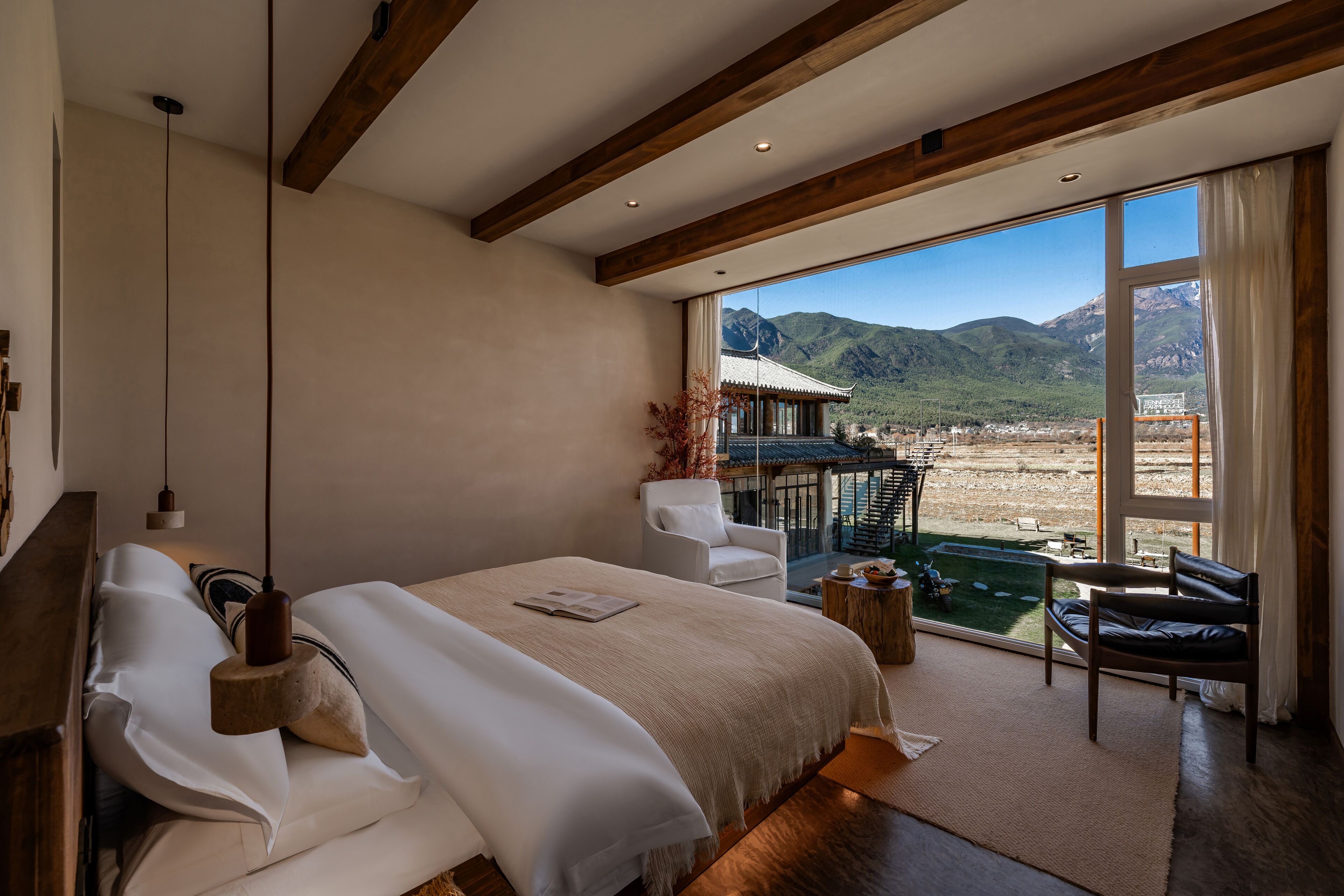 Un dormitorio amplio con una cama grande, vistas a las montañas y un balcón con mobiliario exterior.