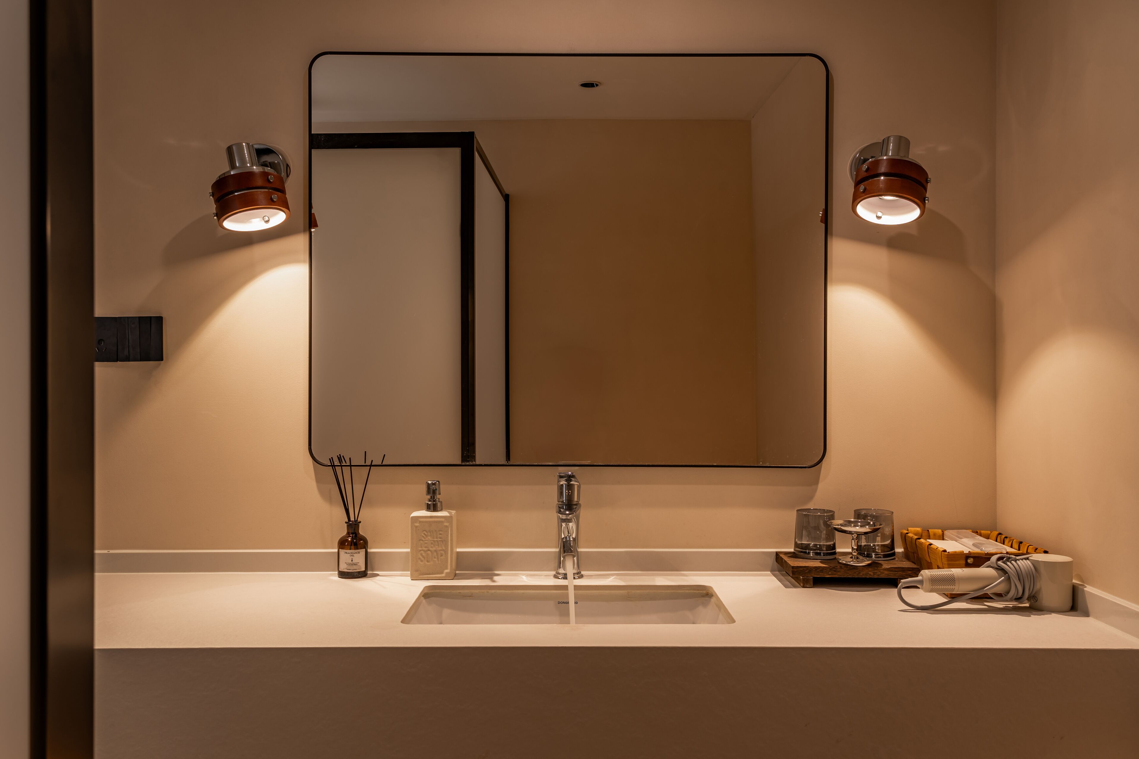 Un baño con un espejo grande, un lavamanos y dos luces empotradas.