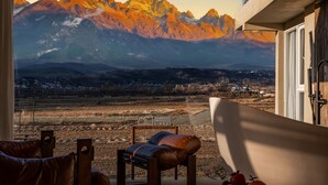 Una habitación con vistas a las montañas, una bañera y una silla.