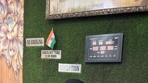 Un área de recepción con un letrero de 'No fumar', un letrero que indica la hora de salida, una bandera india y un letrero que dice 'Recepción'.