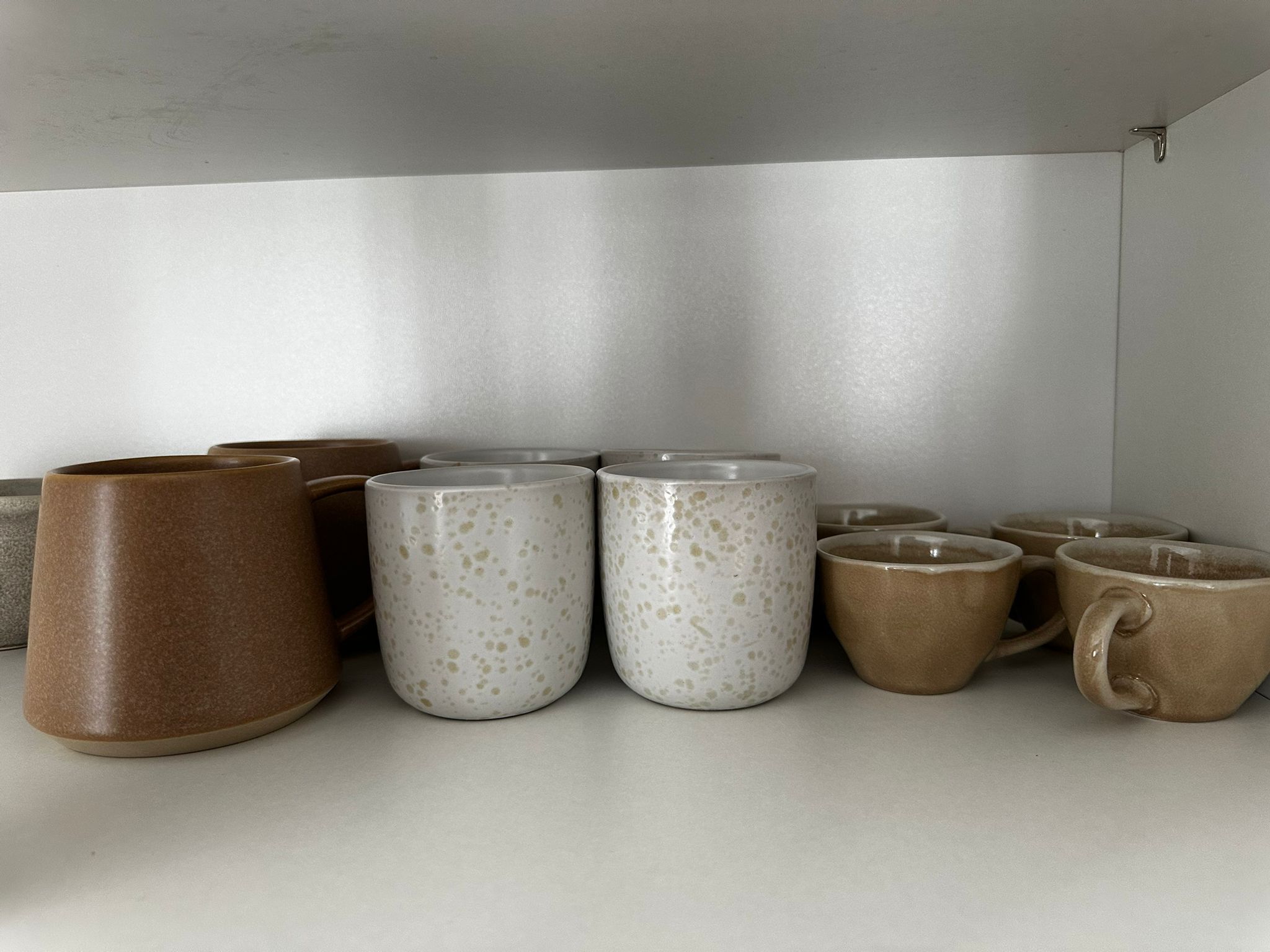 Una colección de tazas de cerámica de distintas formas y tamaños dispuestas en un estante.