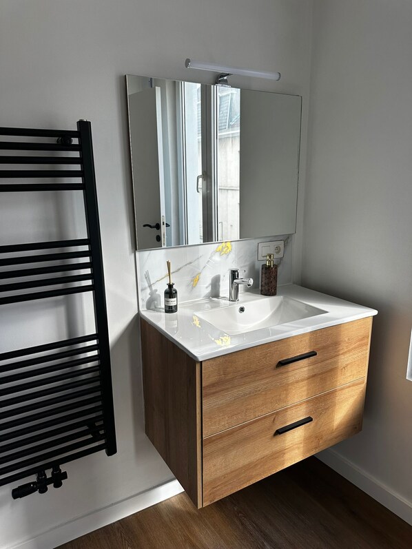 A bathroom with a white vanity, two sinks, a large mirror, and a black towel rack. - Modern 1BR plus LR Apt Near Gravensteen (Ghent)