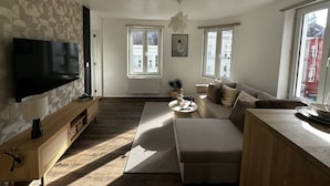 Ein modernes Wohnzimmer mit Flachbildfernseher, einer Couch, einem Couchtisch und einer Wand mit Muster.