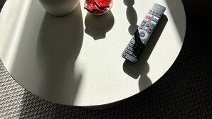 Ein runder Couchtisch mit einer Vase getrockneter Blumen, einer Kerze und einer Fernbedienung.
