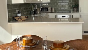 Een moderne keuken met witte kasten, een roestvrijstalen afzuigkap en een betegelde achterwand.